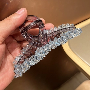 Close-up of a purple resin hair claw clip decorated with sparkling ice blue crystals
