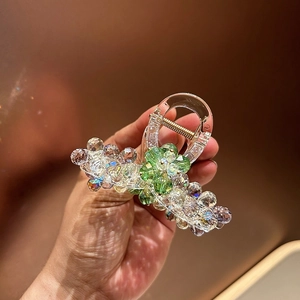 Macro shot of rhinestone claw clip with champagne beads and green crystal floral detail