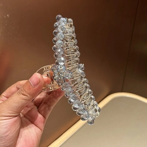 Close-up of luxury hair claw clip with transparent blue crystals and gold metal finish