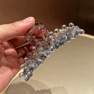 Détail d'une pince à cheveux ambre ornée de perles de cristal bleues et claires
