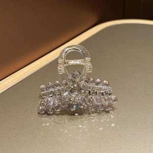 Detail of light purple crystal hair claw clip with floral stones on leather surface