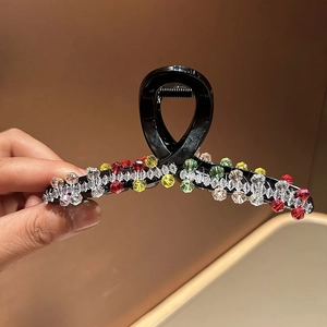 Close-up of elegant hair claw clip with colorful crystal beads and metal spring detail