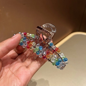Close-up of translucent brown hair claw clip with colorful round crystal beads detail