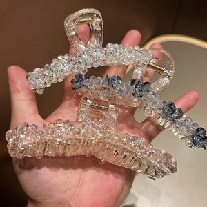 Détail de pinces à cheveux ornées de perles de cristal en finitions irisées et bleu noir