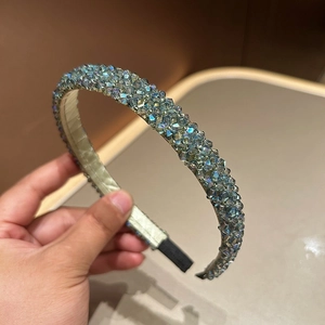 Close-up of sparkling light green crystal beads on the woven wide headband surface