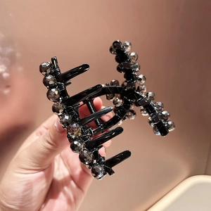 Close-up of a large black hair claw clip with smoke-grey faceted crystal beads detailing