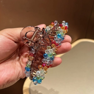 Macro detail of amber resin shark hair claw clip with colorful sparkling crystal beads