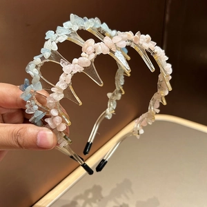Handheld view of two non-slip forest style headbands with blue and pink natural stones