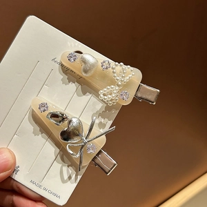 Détail de barrettes en résine jaune avec nœuds en perles et cœurs en strass sur carte