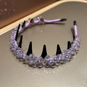 Close-up of purple crystal beads and black spiked comb teeth on a fabric headband