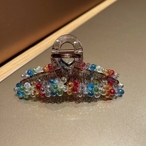 Close-up of elegant hair claw clip with colorful crystal beads and amber resin finish