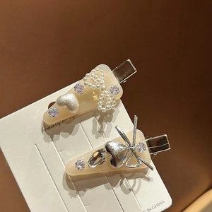 Détail de barrettes en acétate avec nœuds en perles, cœurs et strass brillants sur carte
