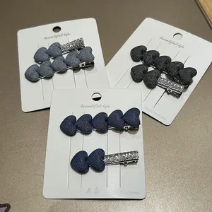 Detailed macro view of denim heart hair clips with rhinestone accents on card