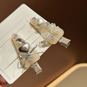 Détails des barrettes crème avec perles, nœuds et strass sur carte de présentation