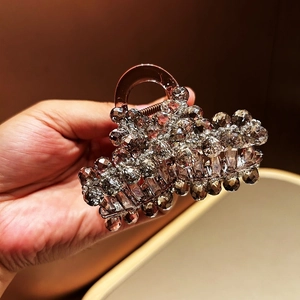 Detailed close-up of large hair claw clip with dark resin and sparkling crystals