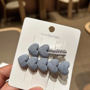 Detailed macro view of denim blue woven heart hair clips with sparkling rhinestone accents