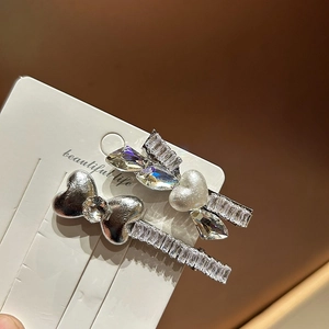 Vista macro di eleganti fermagli per capelli con strass e perle su cartoncino bianco