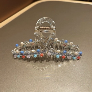 Macro detail of acrylic shark hair claw clip with colorful beads and zircon accents