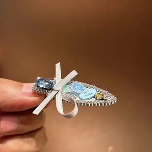 Detailed close-up of a handmade silver hair clip featuring blue gems and silk bow knot