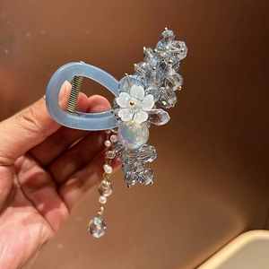 Detail view of a light blue crystal hair claw clip with floral accents and long tassels