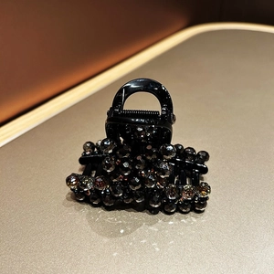 Detail of luxury hair claw clip featuring dark grey crystal beads on a black base