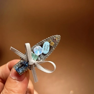 Macro shot of handmade hair clip with rhinestones, blue gem and delicate ribbon bow