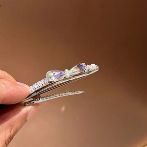 Détail de la pince à cheveux élégante avec cristaux verts, perles et métal argenté