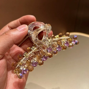 Détail de la pince à cheveux transparente avec des perles violettes et ambrées