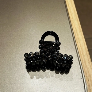 Detail of elegant black beaded hair claw clip with faceted glass pearls on grey surface