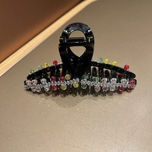 Close-up of elegant black hair claw clip with colorful crystal beads and white rhinestones