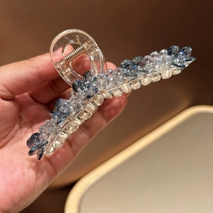 Détail de la pince à cheveux avec cristaux bleus et blancs sur une base transparente