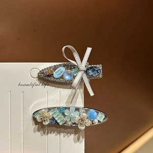 Detailed view of blue rhinestone hair clips with fabric bow on display card