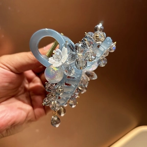 Detailed macro of crystal-beaded hair claw clip with white flower on resin base