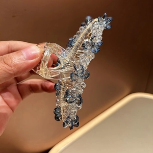 Gros plan des perles de cristal et motifs floraux sur une pince à cheveux bleue