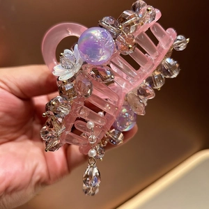 Detailed close-up of pink resin hair claw with colorful crystal beads and pearl tassels
