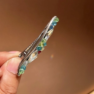 Vue macro des strass colorés sur une pince à cheveux argentée montrant les détails fins