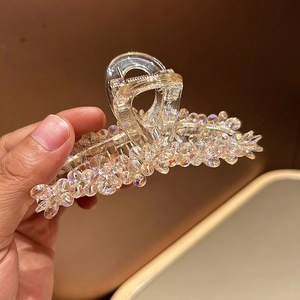 Gros plan d'une pince à cheveux champagne sertie de cristaux brillants dans la main