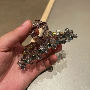 Brown hair claw clip with grey crystal beads decoration in hand view shot