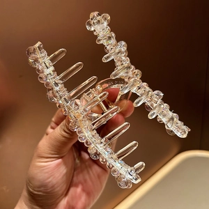 Gros plan détaillé d'une grande pince à cheveux en cristal avec ressort doré et perles irisées