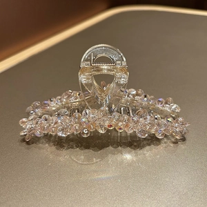Gros plan d'une pince à cheveux en cristal avec perles irisées et ressort métallique