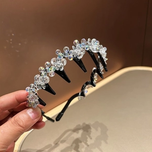 Detail of hand-held black headband featuring sparkling crystal flowers and non-slip comb teeth