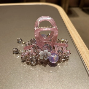 Detailed macro of crystal beads and flower ornaments on a pink resin hair claw clip