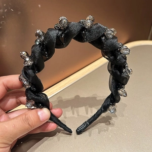 Close-up of twisted black headband with sparkling gray crystals and woven fabric texture