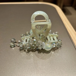 Detail of mint green hair claw with colorful handmade crystal beads and floral accents