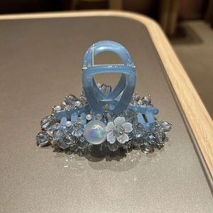 Close-up of handmade blue crystal beaded hair claw clip with floral pearl accents