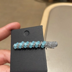 Elegant sky blue beaded hair clip with silver accents and rhinestones on black card