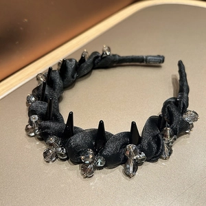 Close-up of black mesh headband with dark grey crystals and punk style metallic spikes