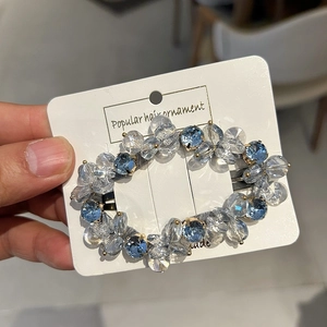 Detail of handcrafted blue crystal hair clip with beaded design on branded card