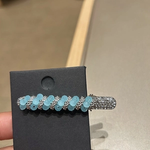 Detail of a luxury hair clip featuring light blue beads and sparkling crystals on silver metal