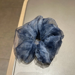 Close-up detail of dark blue organza scrunchie with sparkling glitter and silver sequins